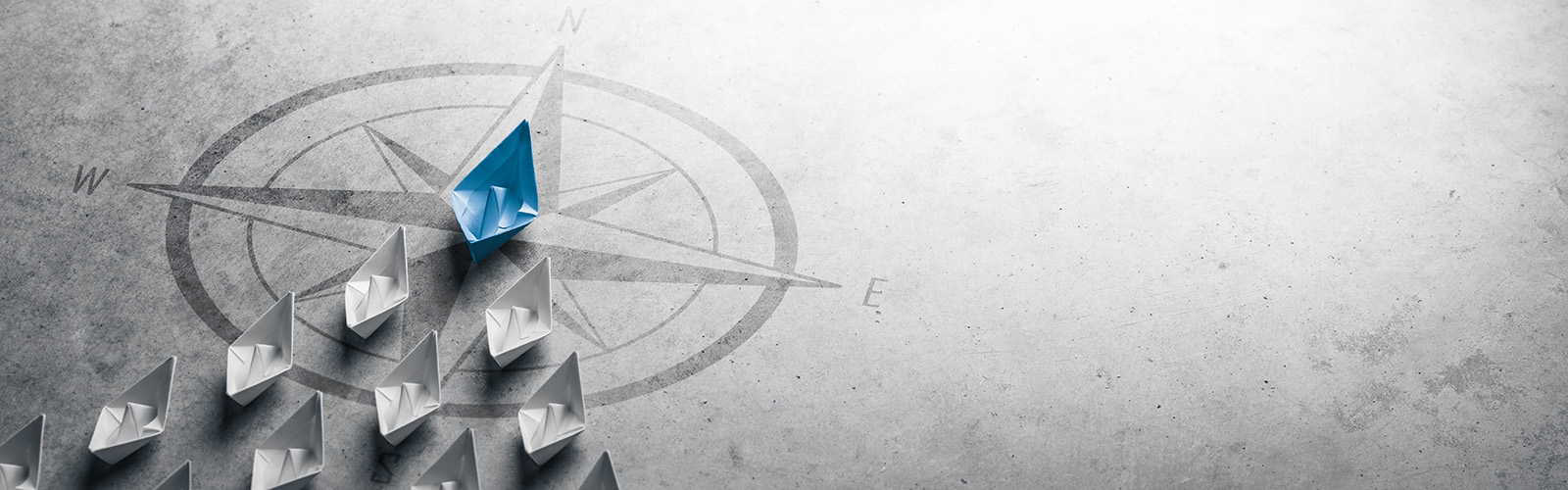 A blue paper boat leads a fleet of white paper boats on a course north.